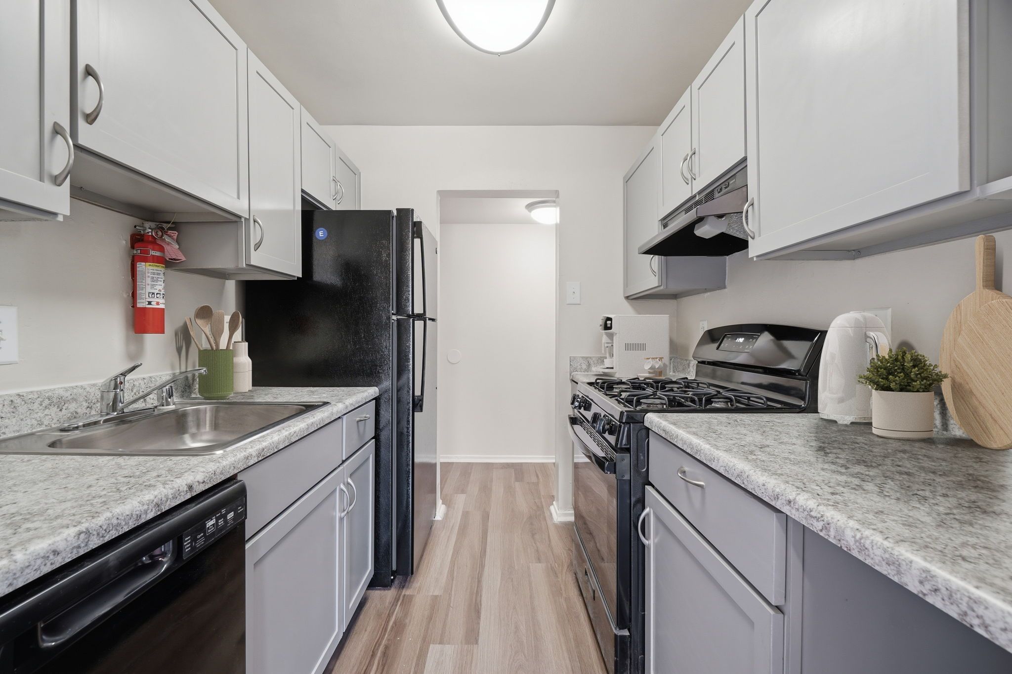 A kitchen with a black refrigerator and a wooden cutting board on the counter.